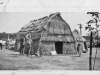 " print of tule huts with peaked roofs. Back says "At County